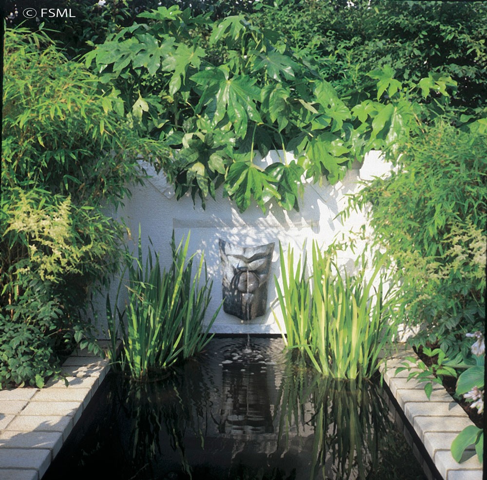 Splashing wall water spout stirs the surface of this serene pond.